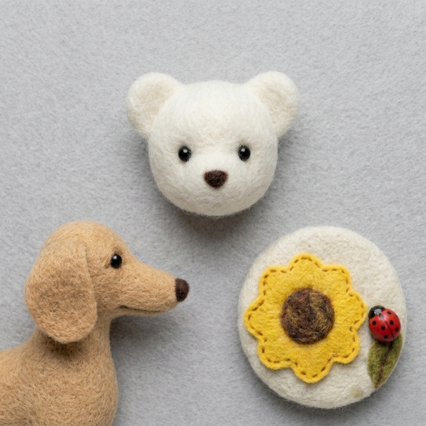 Miniature wool felted crafts including a white bear head, a brown dog head, and a yellow sunflower design.