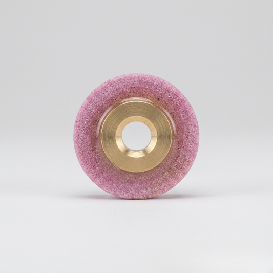 a professional pink whetstone blade sharpener with a brass center hub, designed for industrial rotary fabric cutters, isolated on a seamless white background.