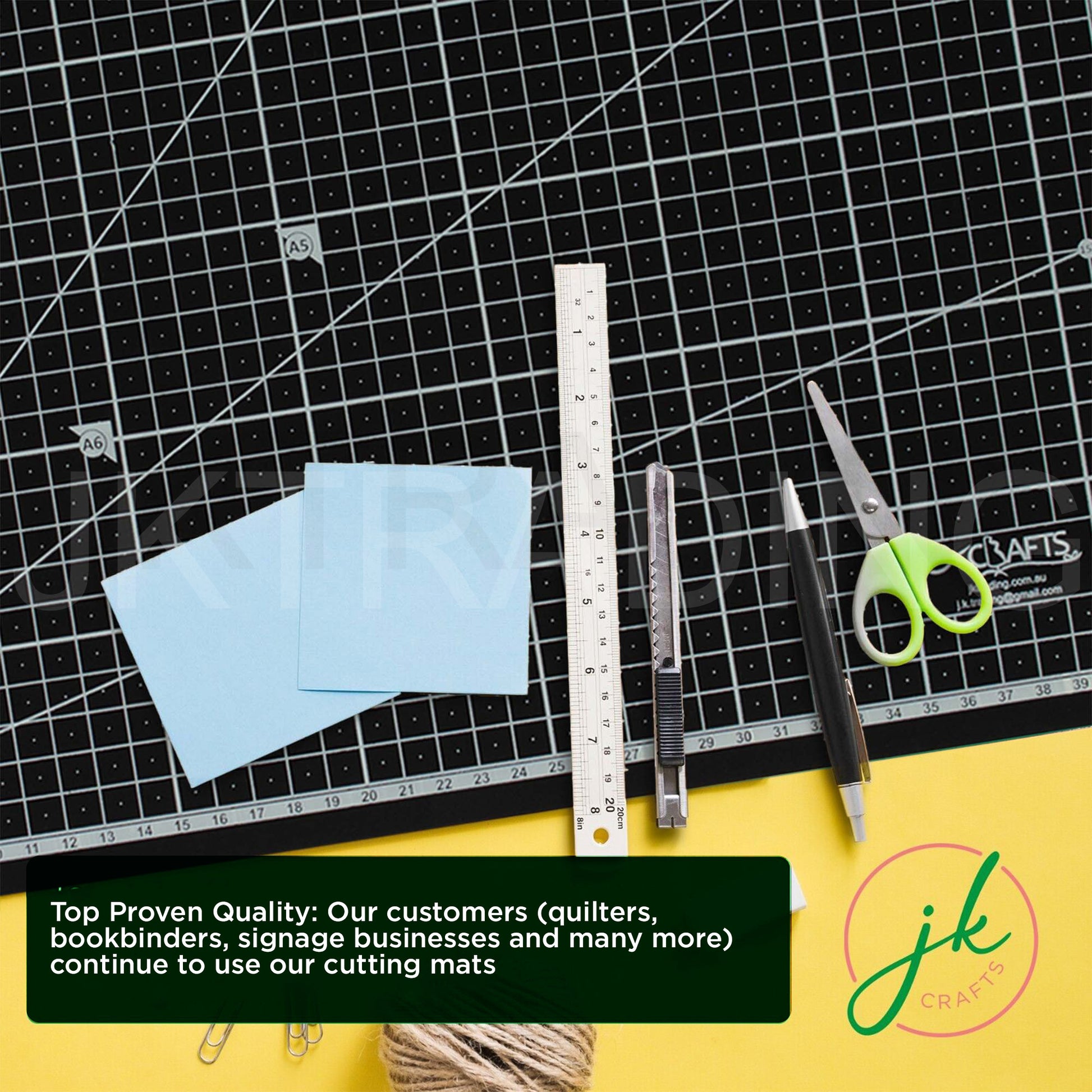 Black heavy-duty A1 self-healing grid cutting mat arranged on a creative desk with craft tools, scissors, a steel ruler, and utility pens.