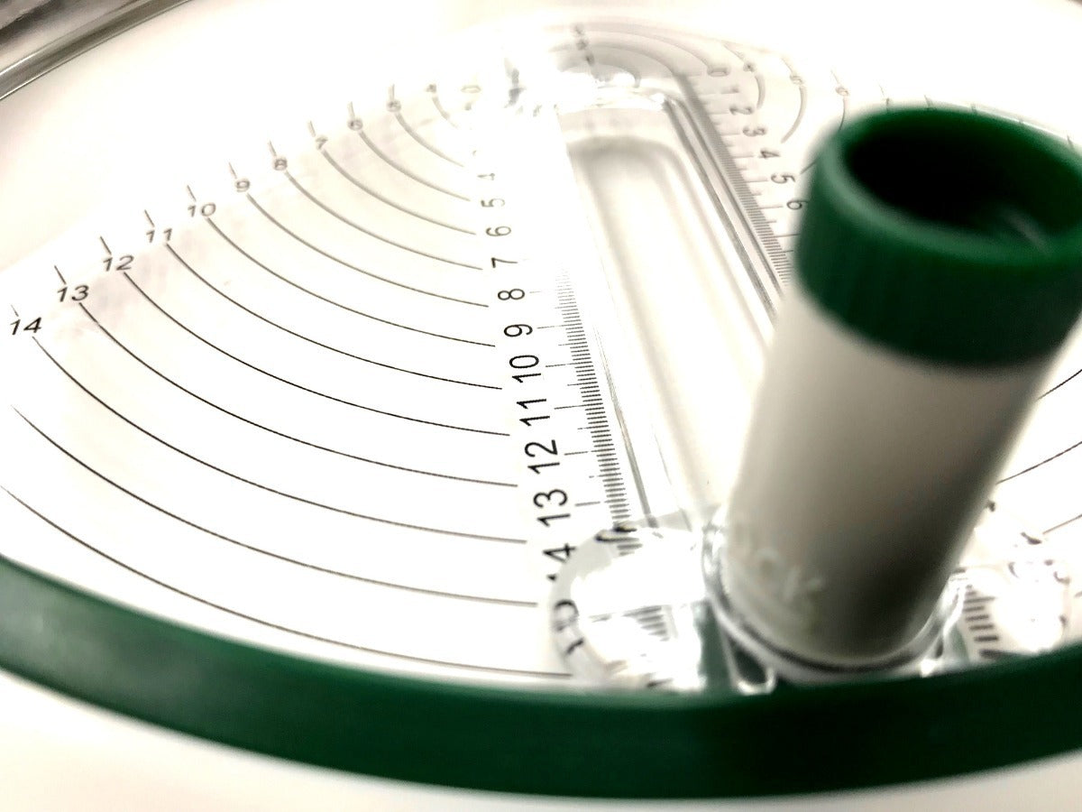 Close-up of a circular measuring device with a green rim and white central part.