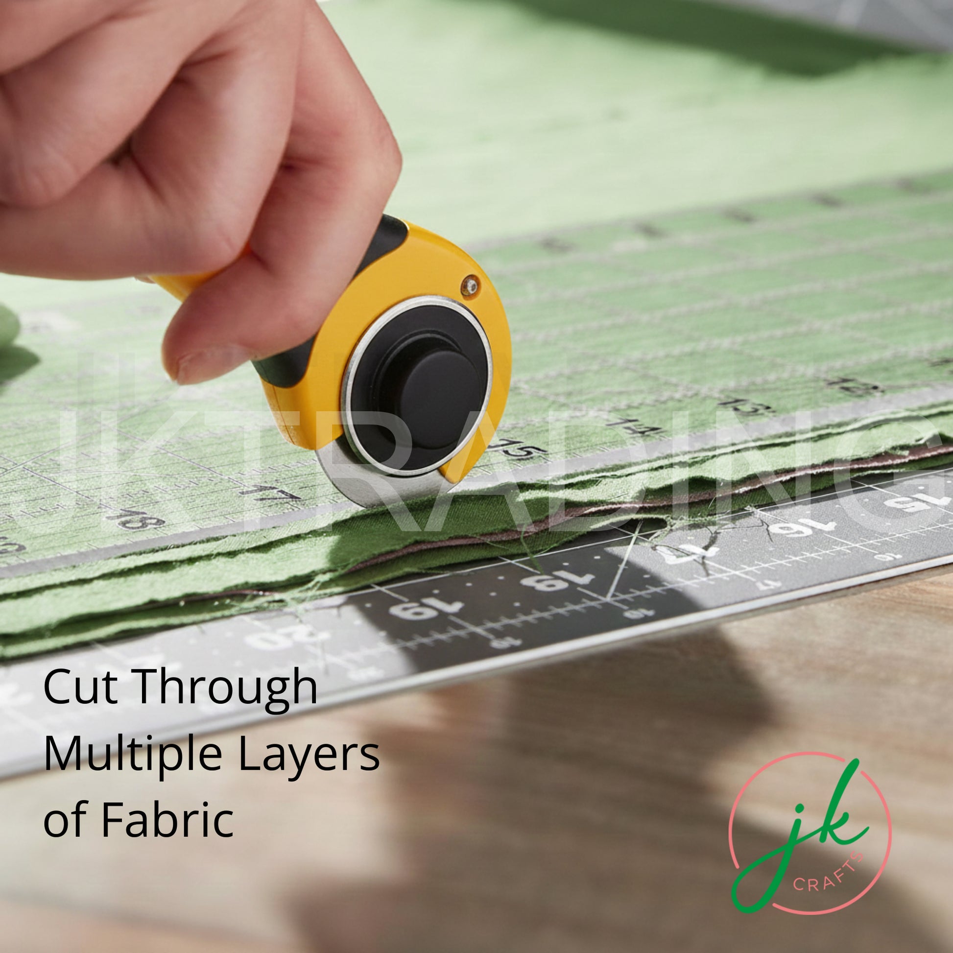 Crafter pushing a rolling rotary fabric cutter along an acrylic patchwork ruler to trim textured green cloth.