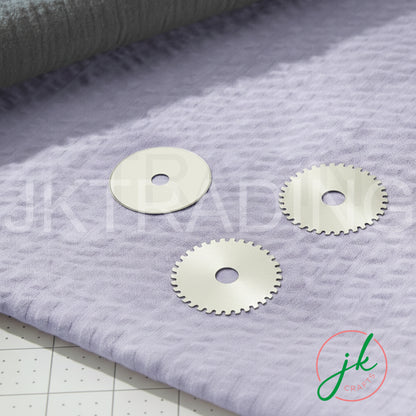 Three steel rotary cutter replacement discs arranged flat on a textured purple wool background.