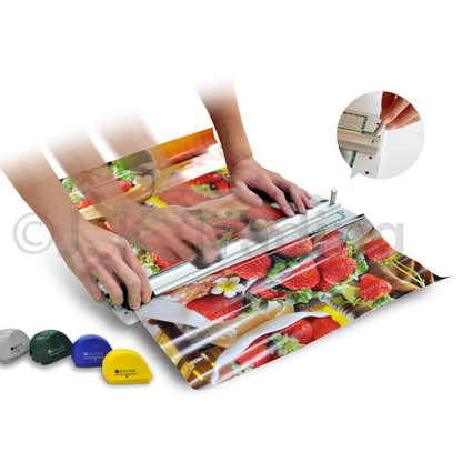 Hands operating a desktop multi-blade rotary paper trimmer system to slice and score colorful holiday gift wrapping paper.