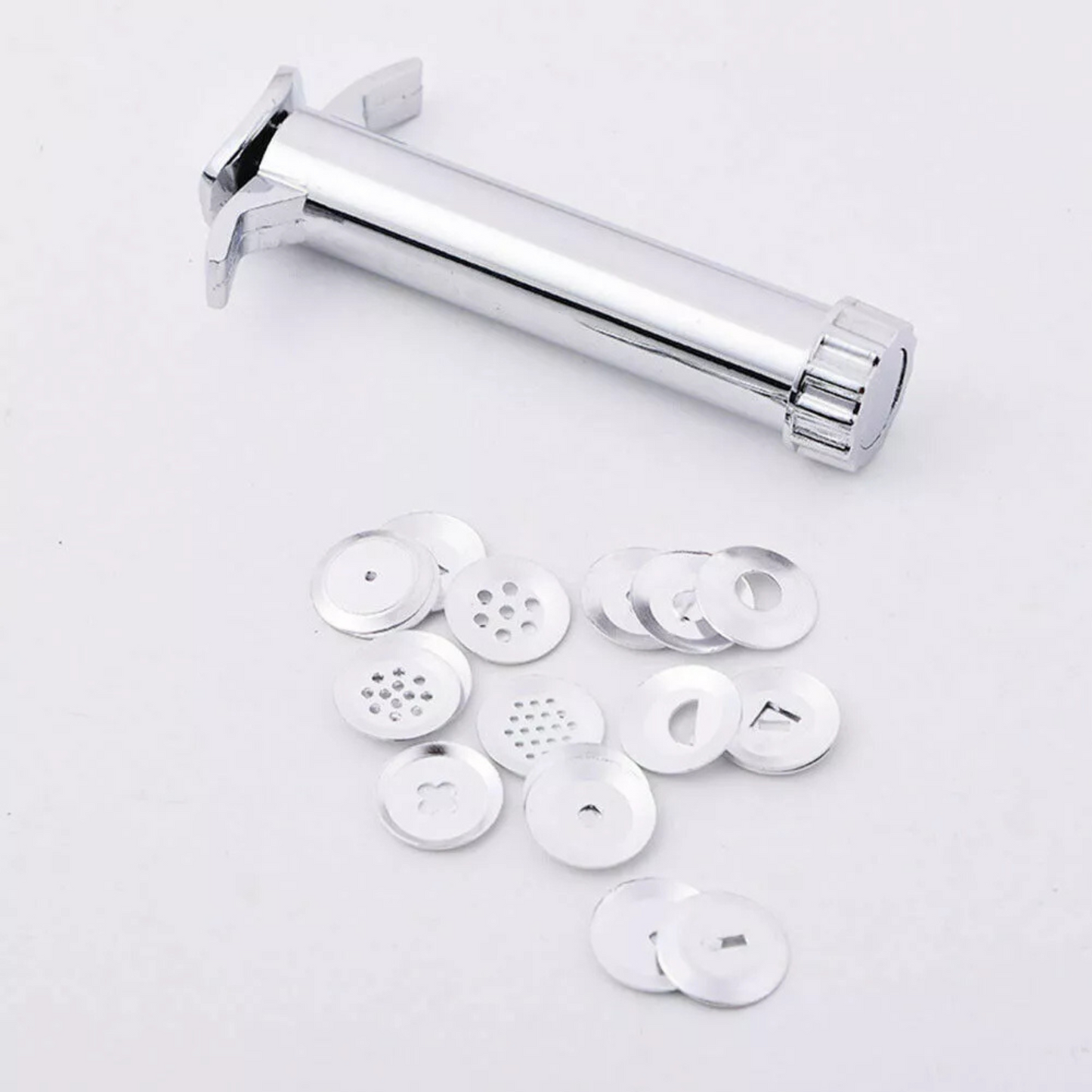 Polished metal icing and sculpting gun kit surrounding by its circular interchangeable steel pattern washers.
