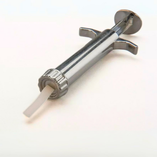 Handheld craft extruder gun pressing out a square strip of white polymer modeling clay onto a flat surface.