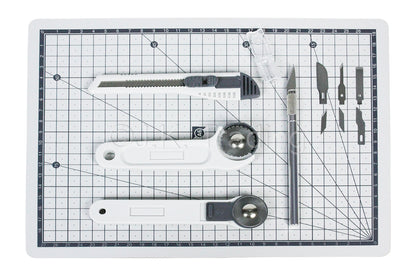 5-piece precision craft tool kit neatly arranged with a carving knife set, steel rule, and a gridded protective workbench pad.