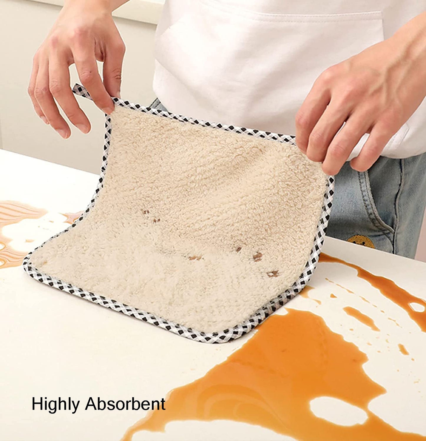 Person holding a fluffy white towel over a spill with text 'Highly Absorbent'.