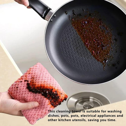 Cleaning a greasy frying pan with a pink cleaning towel over a sink.