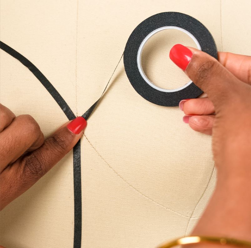 Person using black tape to mark a line on a beige surface