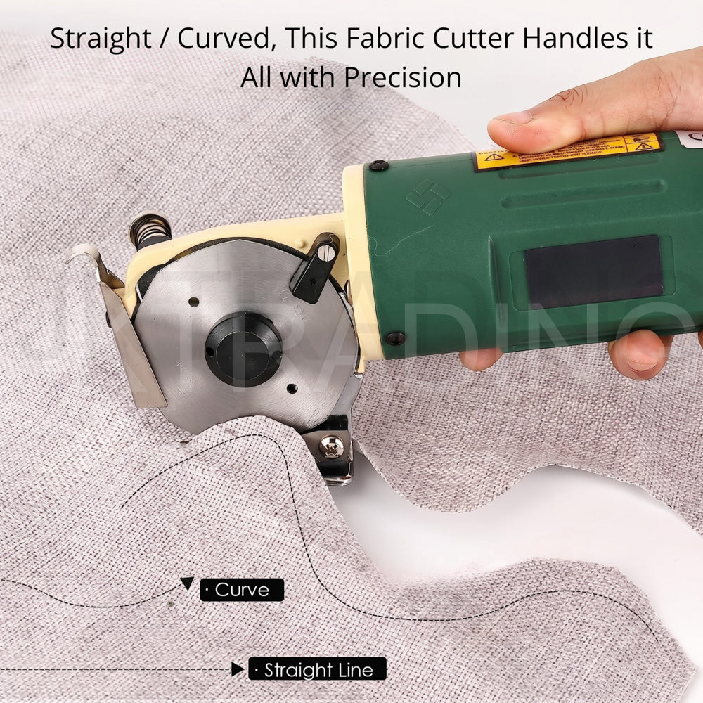 Guided close-up of the electric textile shears tracing an intricate curved pattern line on light grey fabric.