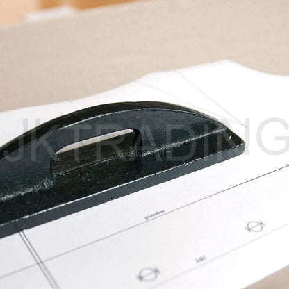 Heavy black iron weight holding down white paper apparel patterns smoothly on a studio cutting table.