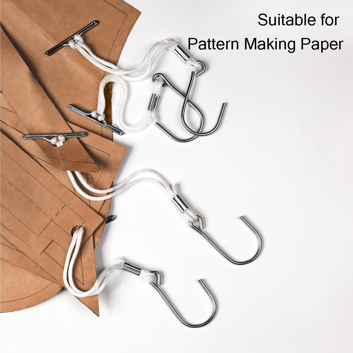 Close-up of metal t-bar hooks securely holding thick brown kraft block patterns in a design workshop.
