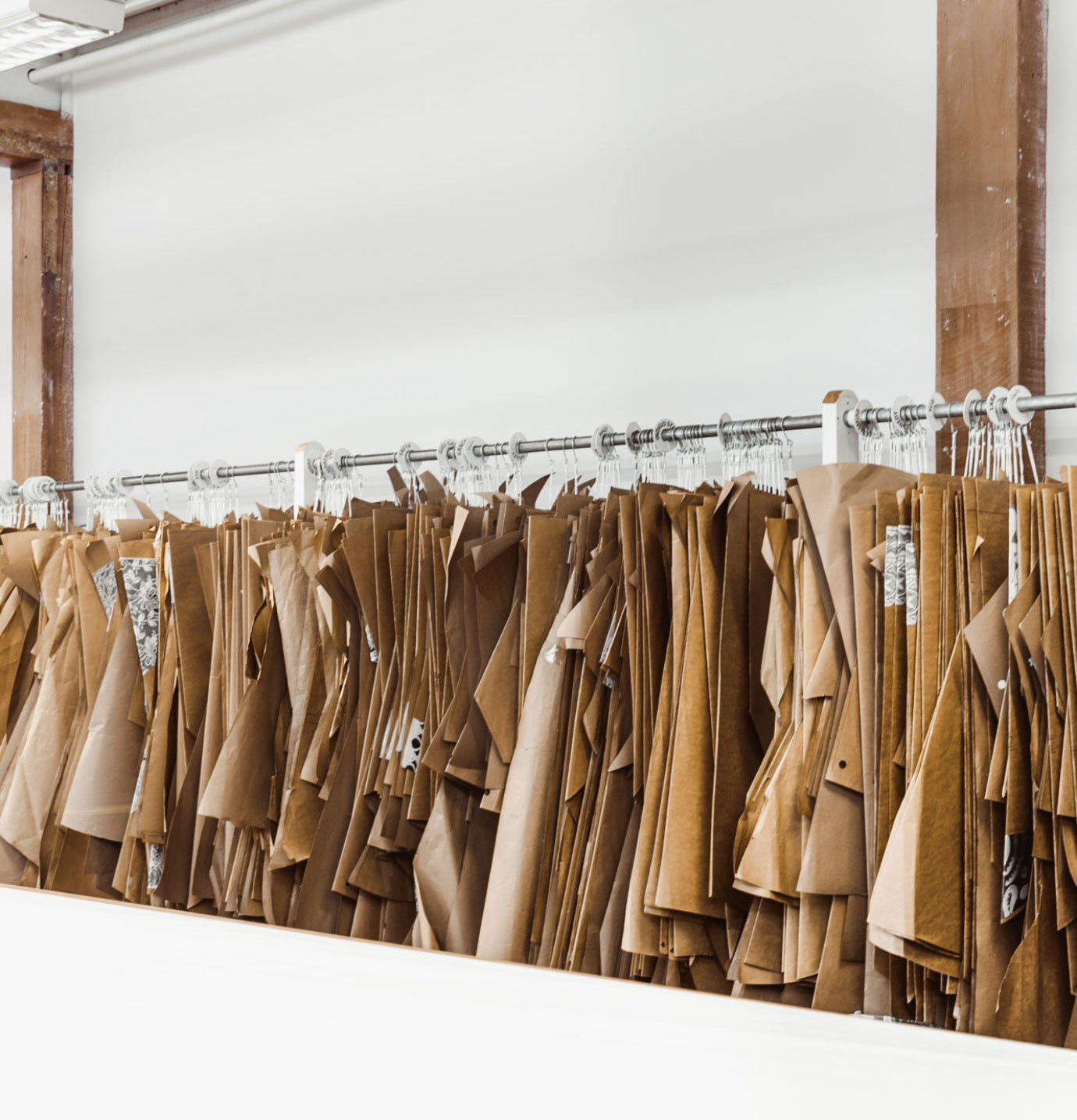 Rows of custom apparel slopers hanging organized on high garment racks in a commercial production facility.