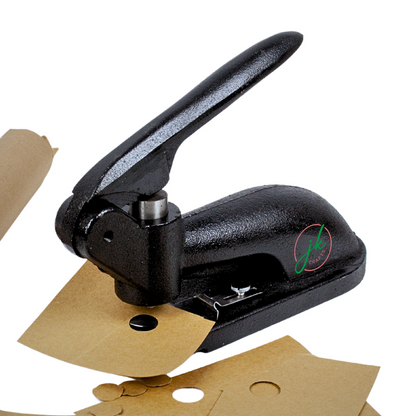 Heavy duty black metal pattern notch punch tool cutting clean holes into thick brown craft paper sheets.