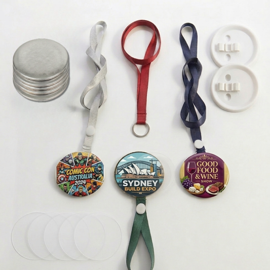 Assorted JKCrafts lanyard button badges in red, blue, green, and silver with custom printed graphic designs.