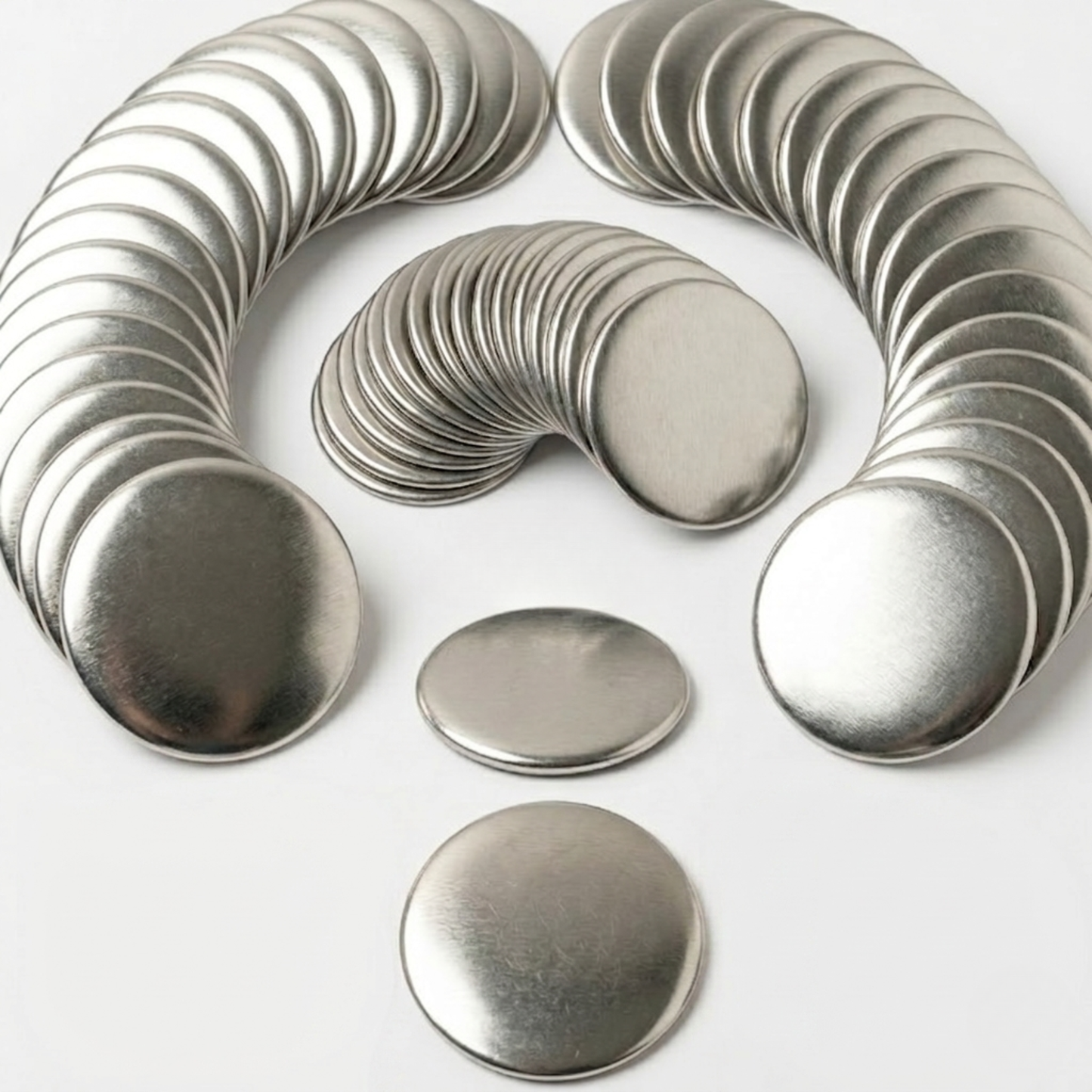 Arched stacks of blank round metal front shells for DIY button badge maker press machines.