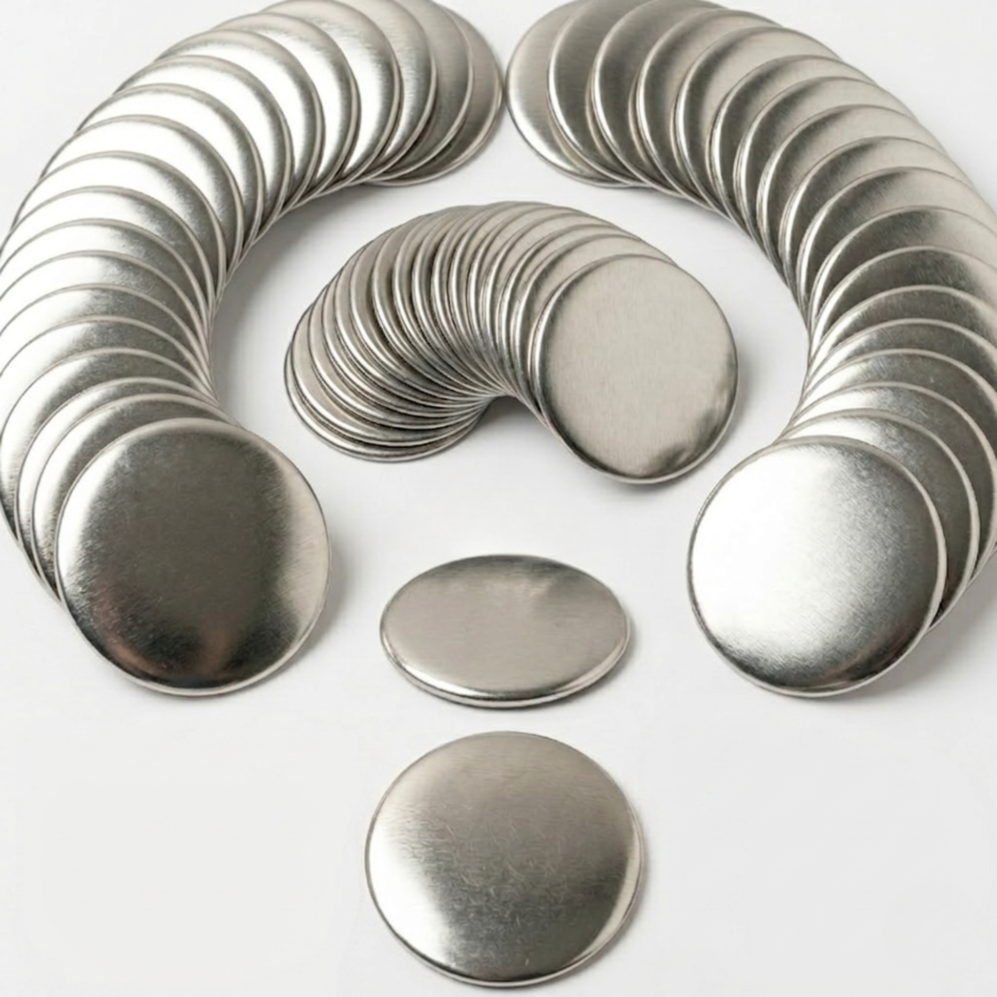 Arched stacks of blank round metal front shells for DIY button badge maker press machines.