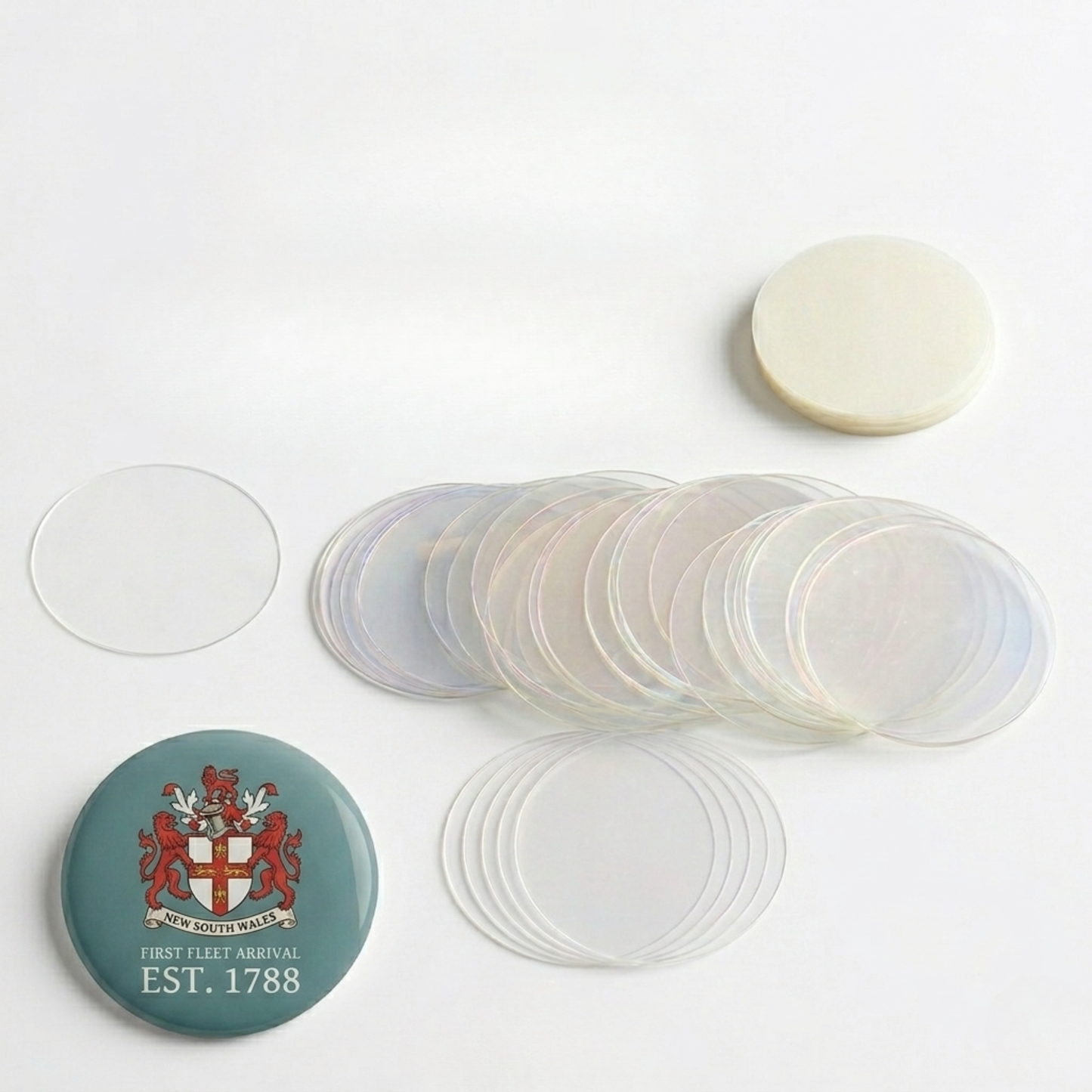 Stack of clear mylar plastic film circles next to a completed custom graphic button badge.
