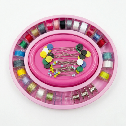 Pink thread holder with colorful threads and pins on a white background