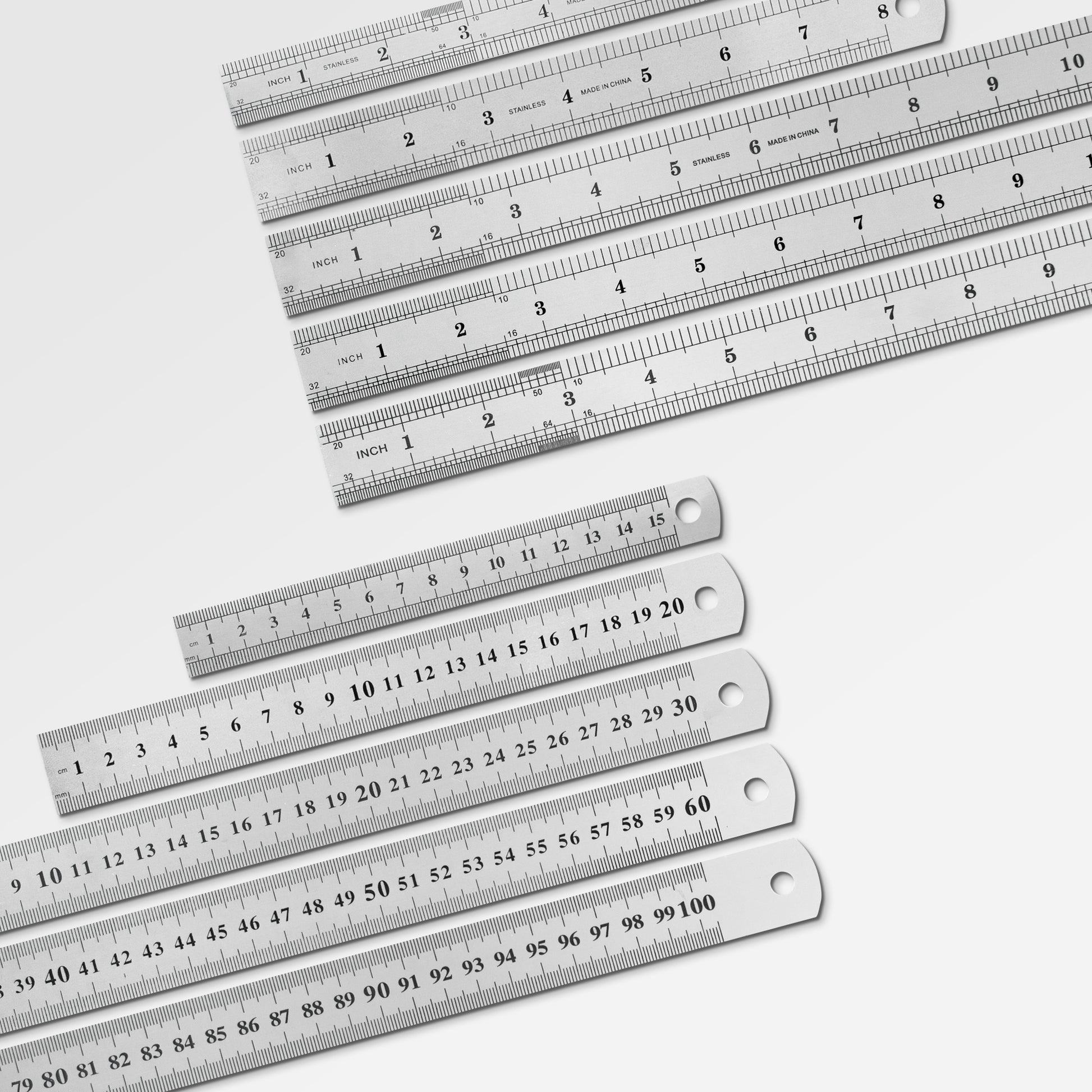 Sorted stack of durable metal workshop rulers ranging from small pocket sizes to large drafting sizes.