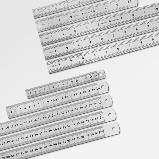 Sorted stack of durable metal workshop rulers ranging from small pocket sizes to large drafting sizes.