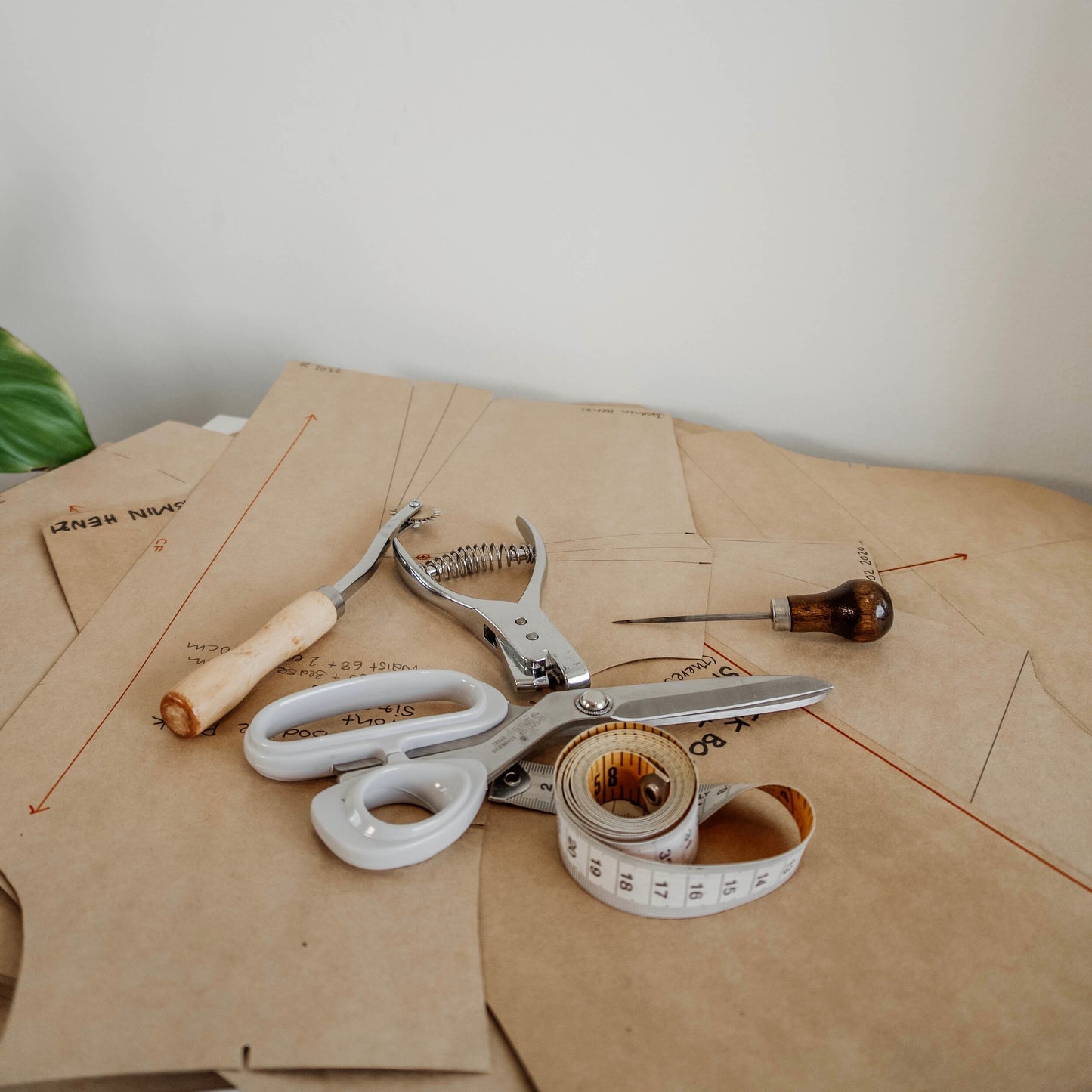 Complete fashion design workshop setup featuring a pattern notcher tool, sewing scissors, and tape measure.