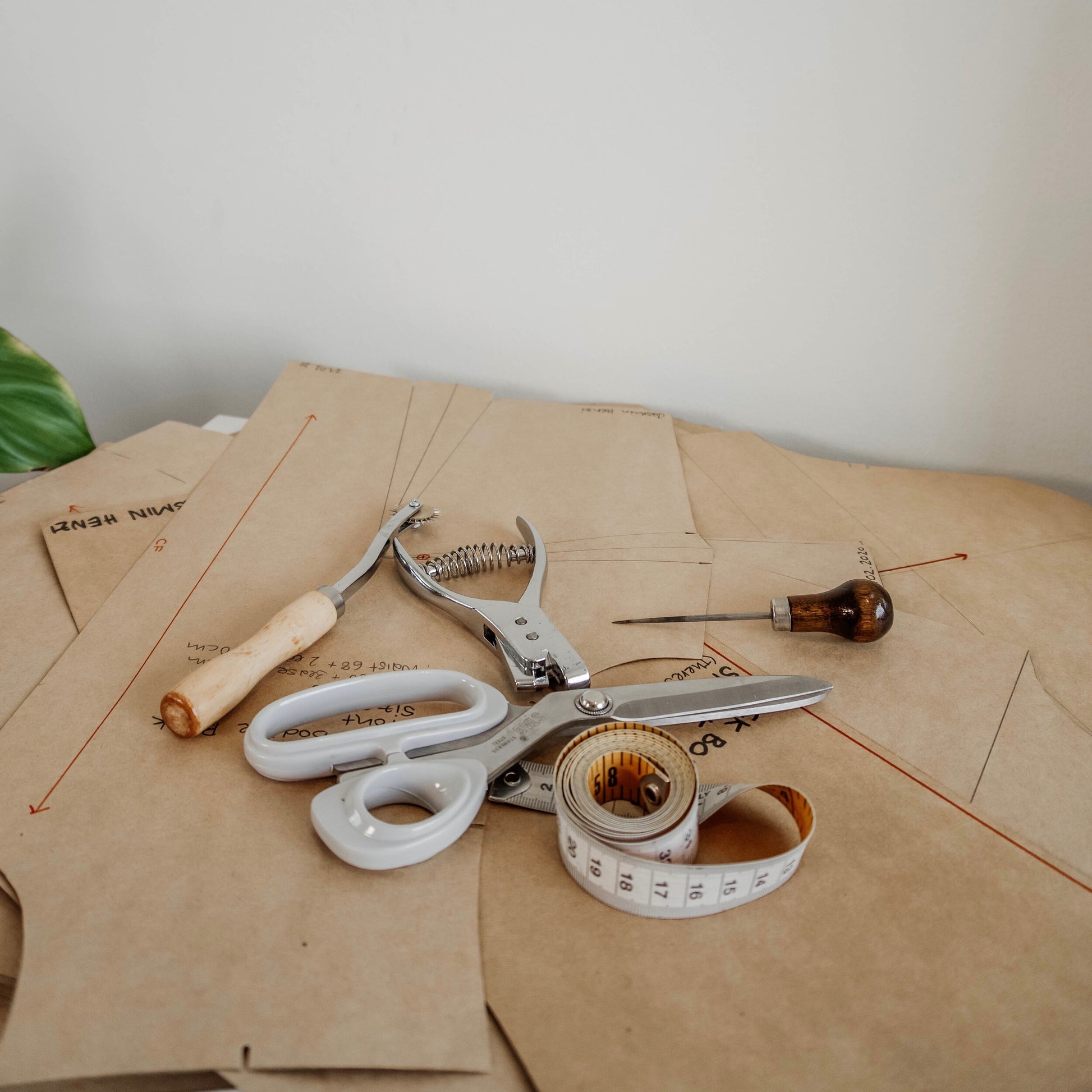 Complete fashion design workshop setup featuring a pattern notcher tool, sewing scissors, and tape measure.