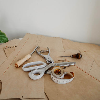 Complete fashion design workshop setup featuring a pattern notcher tool, sewing scissors, and tape measure.