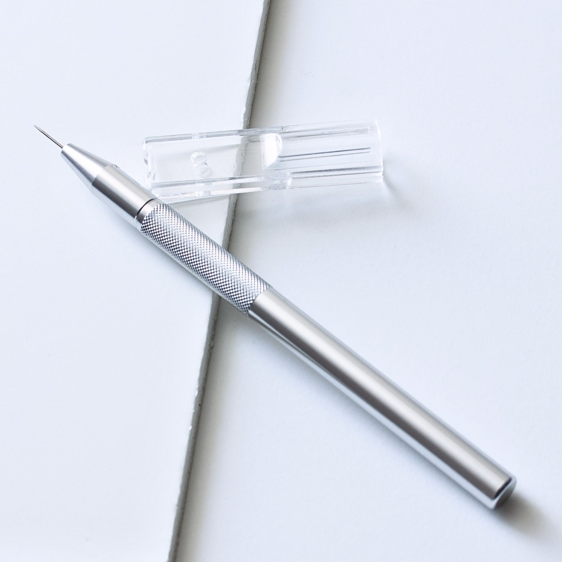 Premium silver aluminium single-pin parchment craft perforating tool shown with its clear plastic protective needle cap.