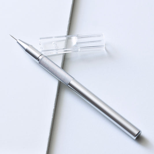 Premium silver aluminium single-pin parchment craft perforating tool shown with its clear plastic protective needle cap.