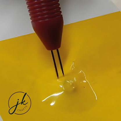 Detailed demonstration showing a multi-needle styling tool punching accurate decorative line points into yellow cardstock.
