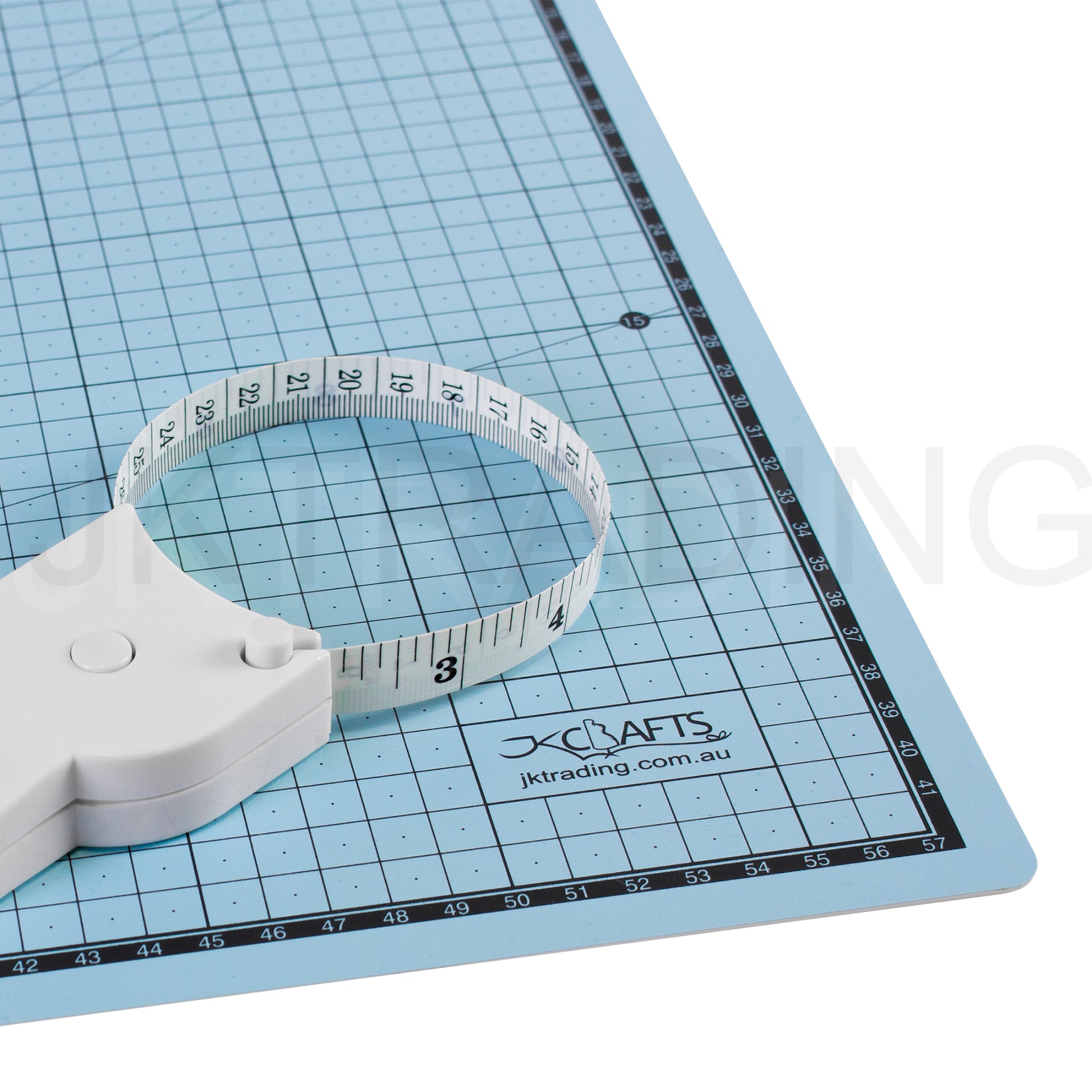 Telescopic waist and body tape measure resting extended on a blue gridded self-healing cutting mat workspace.