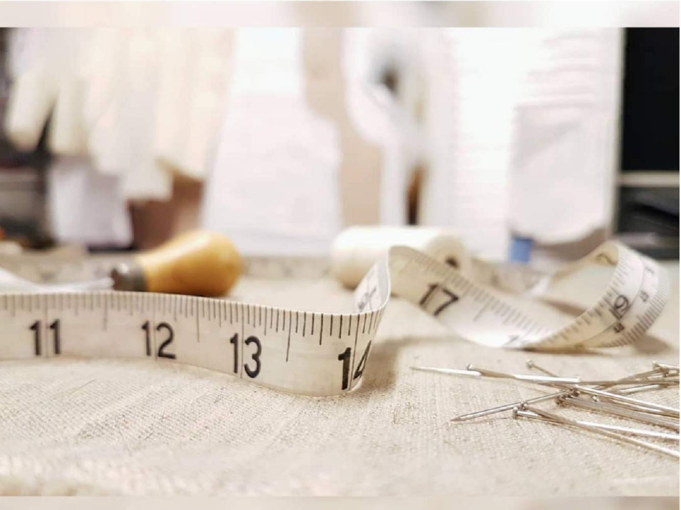 Measuring tape and sewing tools on a fabric surface with a blurred background