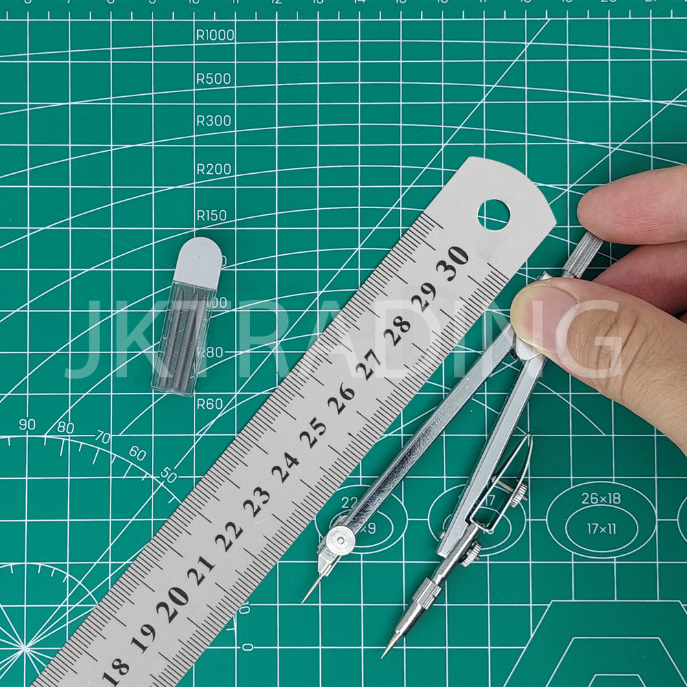 Hand holding a short stainless steel pocket ruler over a green self-healing grid grid cutting mat.