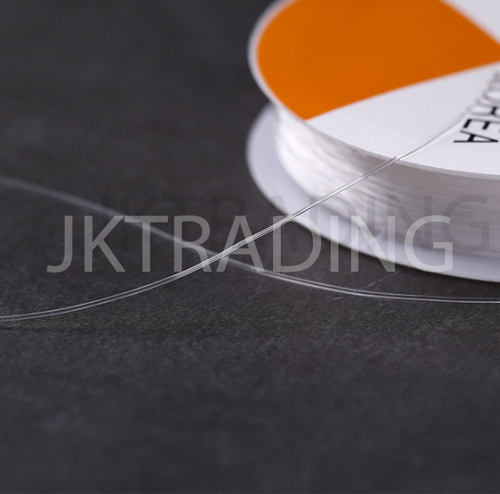 Close-up of a spool of clear thread with an orange label on a dark background.