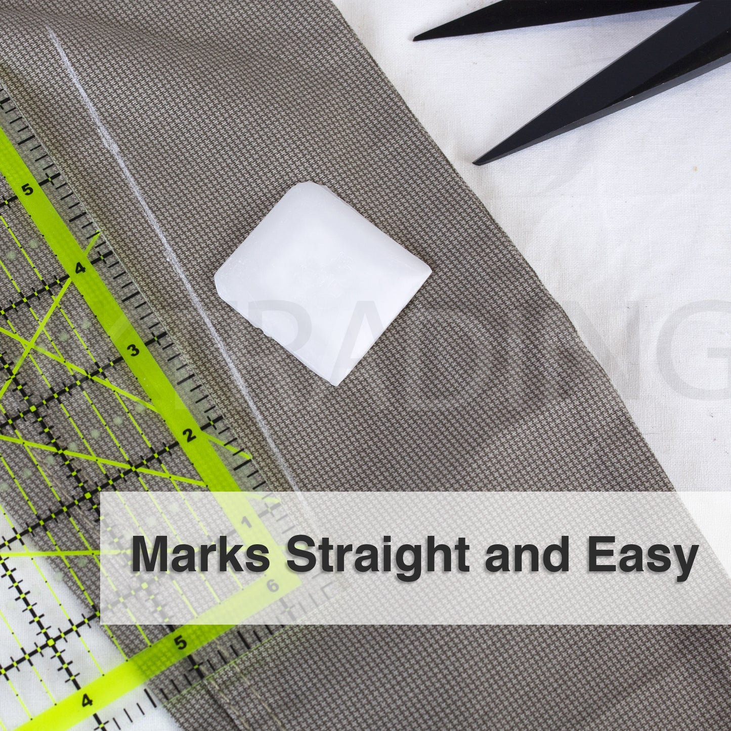 Square white tailors wax marker drafting smooth, straight lines on khaki garment fabric using a clear grid ruler.