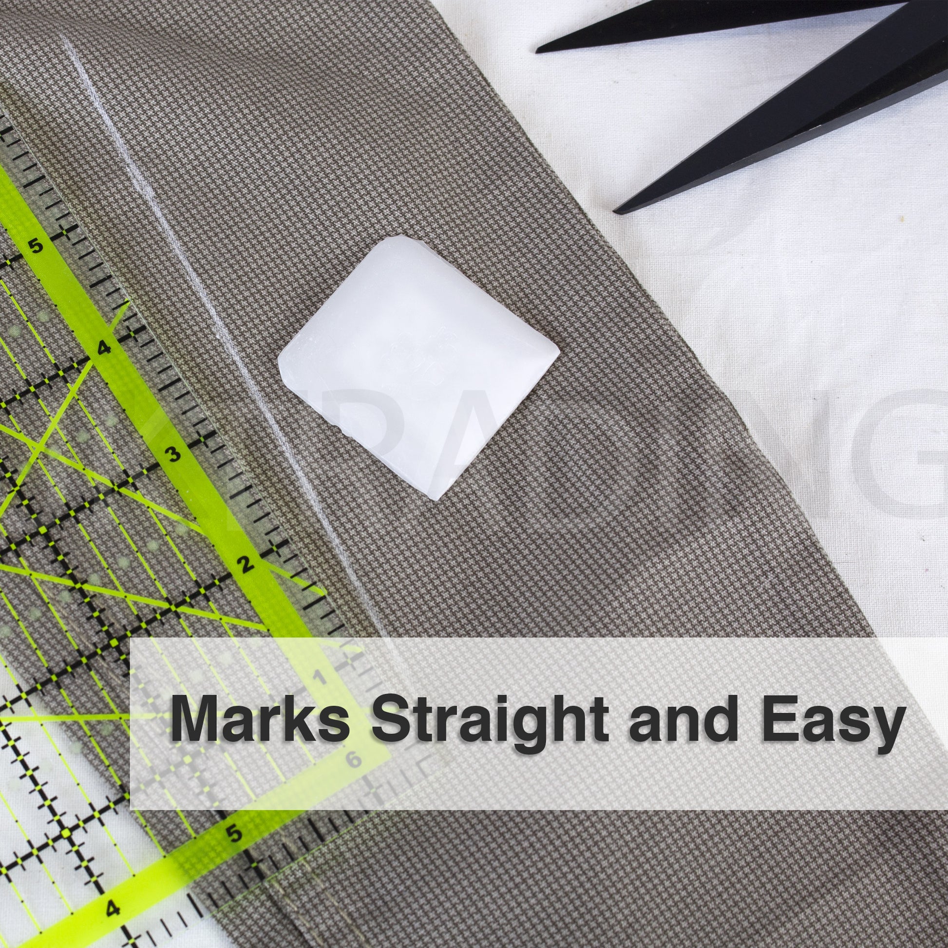 Square white tailors wax marker drafting smooth, straight lines on khaki garment fabric using a clear grid ruler.