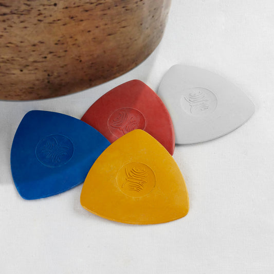 Four vibrant triangular tailors chalk blocks in blue, red, yellow, and white fanned out on a table.