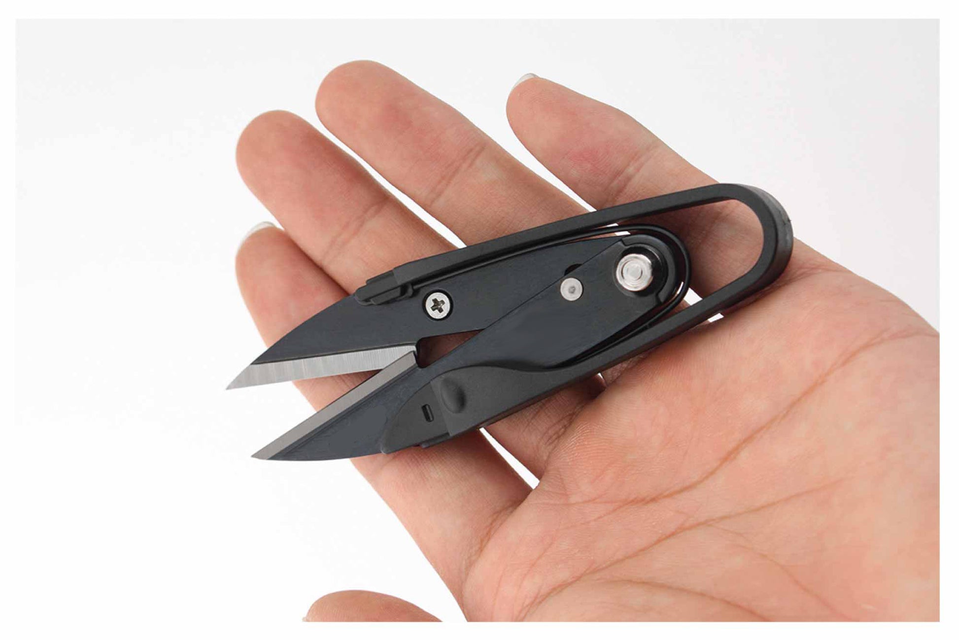 Single black pocket embroidery yarn cutter resting flat in an open hand to showcase its ultra-lightweight portability.